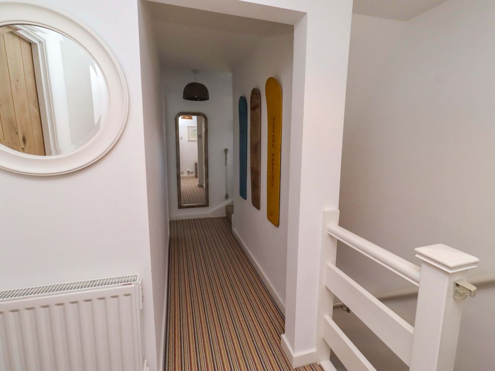 A hallway with a mirror and decorative boards at Dunford Cottage in Bamburgh