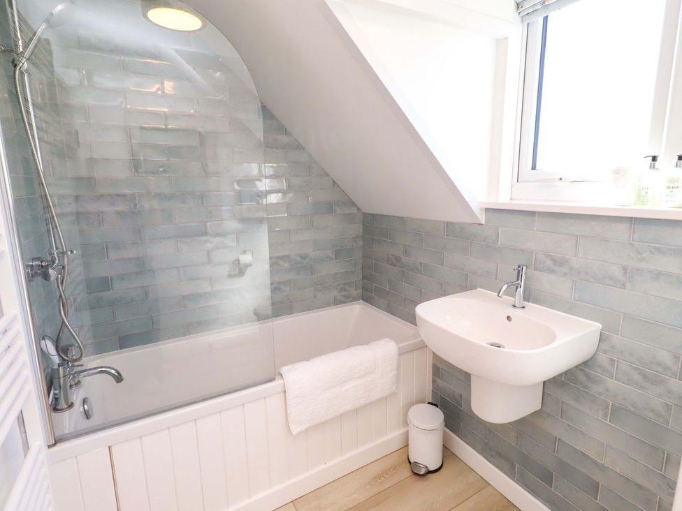 A bathroom with a bathtub, sink, and window at Dunford Cottage in Bamburgh