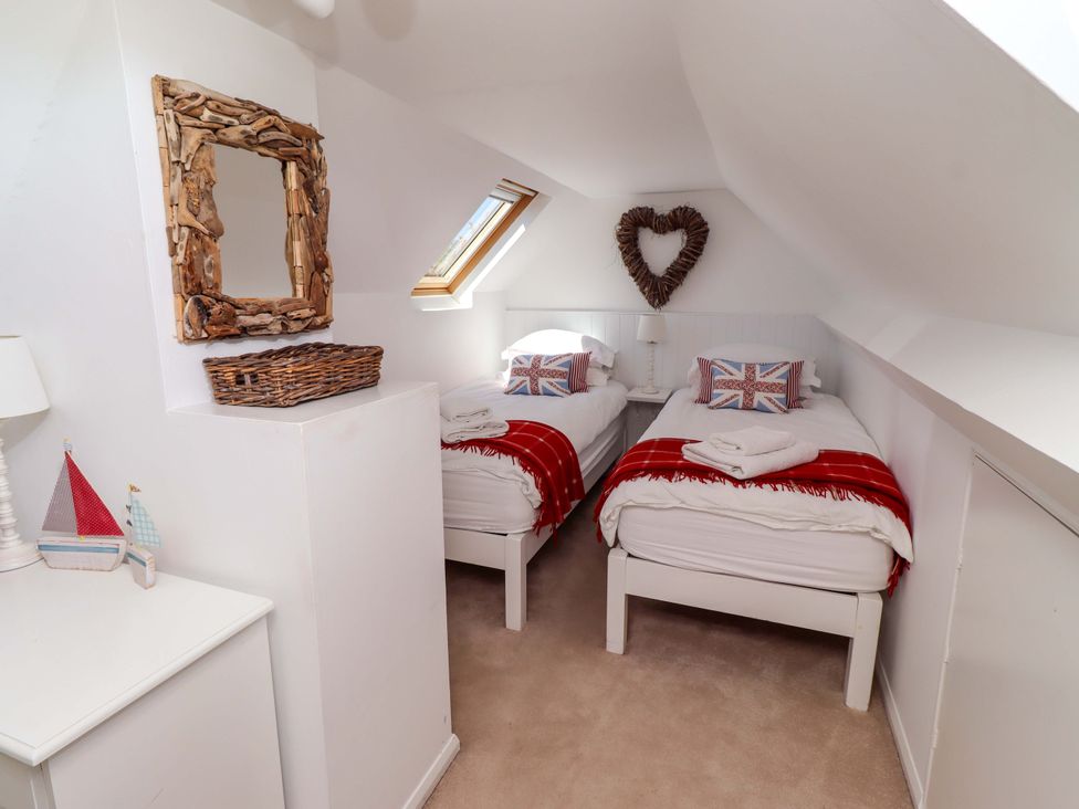 A bedroom with twin beds and a decorative mirror at Dunford Cottage Bamburgh