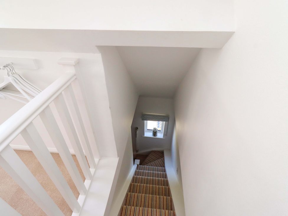 A staircase with a railing and window at Dunford Cottage Bamburgh