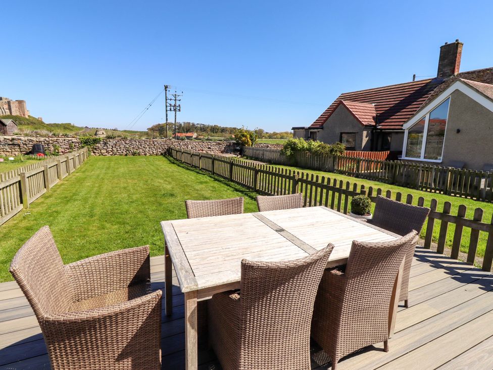 An outdoor patio with a wooden table and chairs at Dunford Cottage Bamburgh