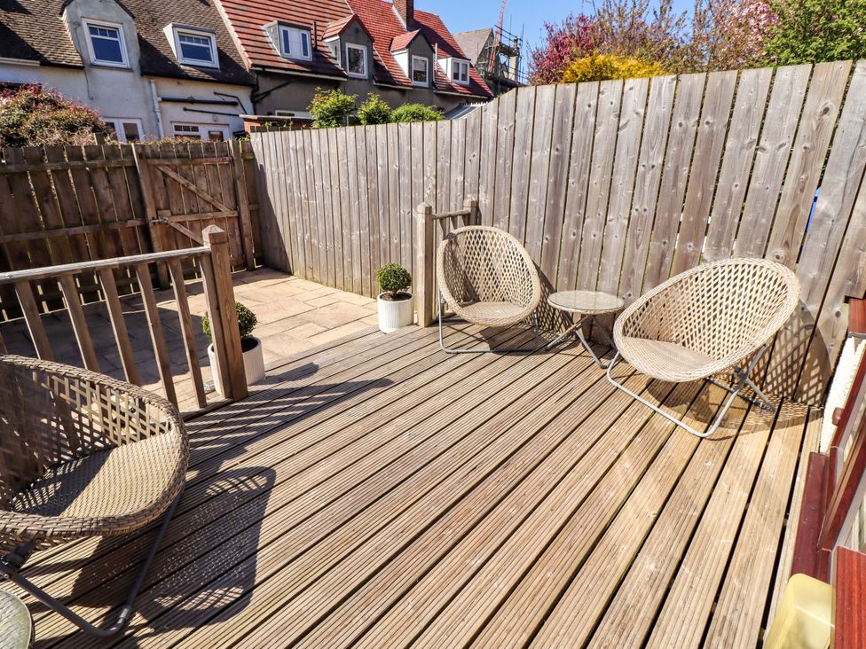 An outdoor deck area with chairs and a table at Dunford Cottage in Bamburgh