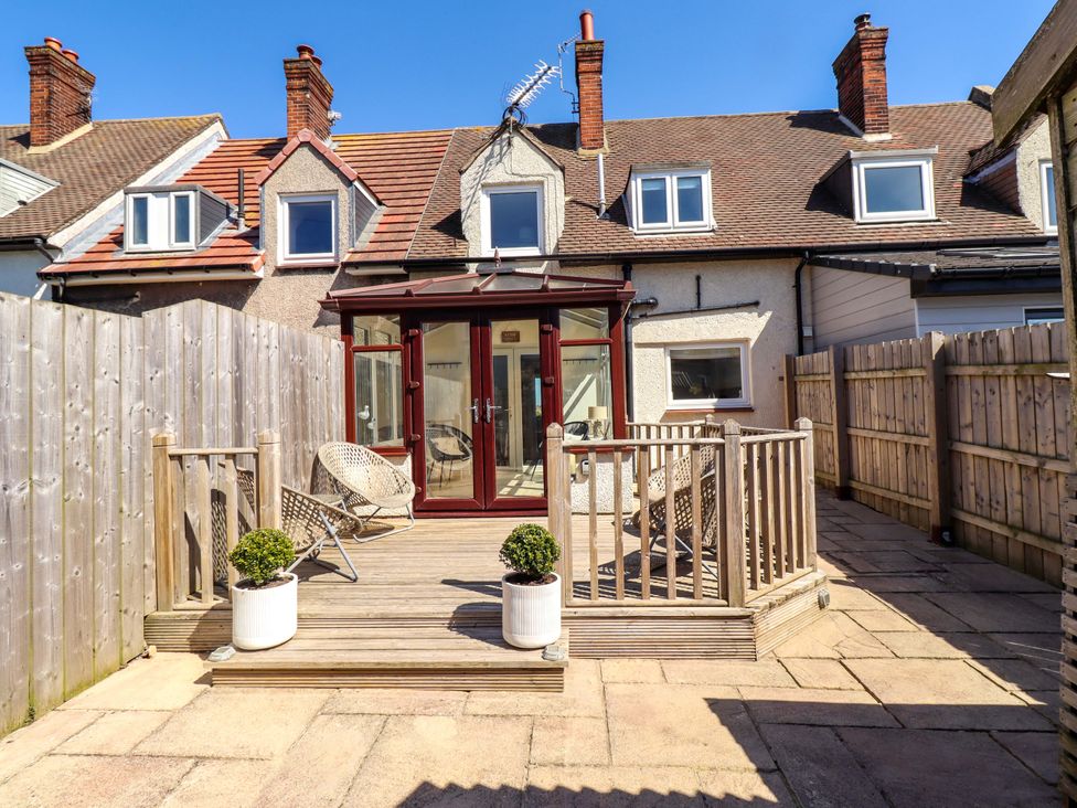 A garden with wooden decking and glass doors at Dunford Cottage in Bamburgh