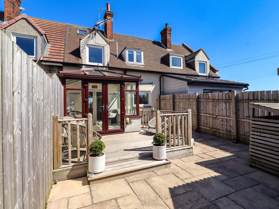 An outdoor area with a deck and chairs at Dunford Cottage in Bamburgh