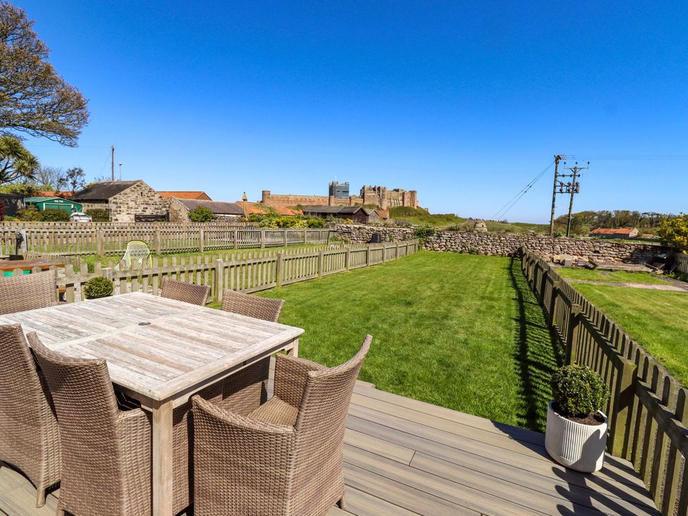 A garden with a seating area and a view of a castle at Dunford Cottage in Bamburgh