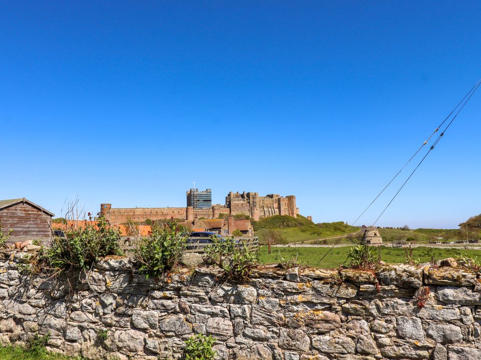 A castle view with a stone wall and shed at Dunford Cottage Bamburgh
