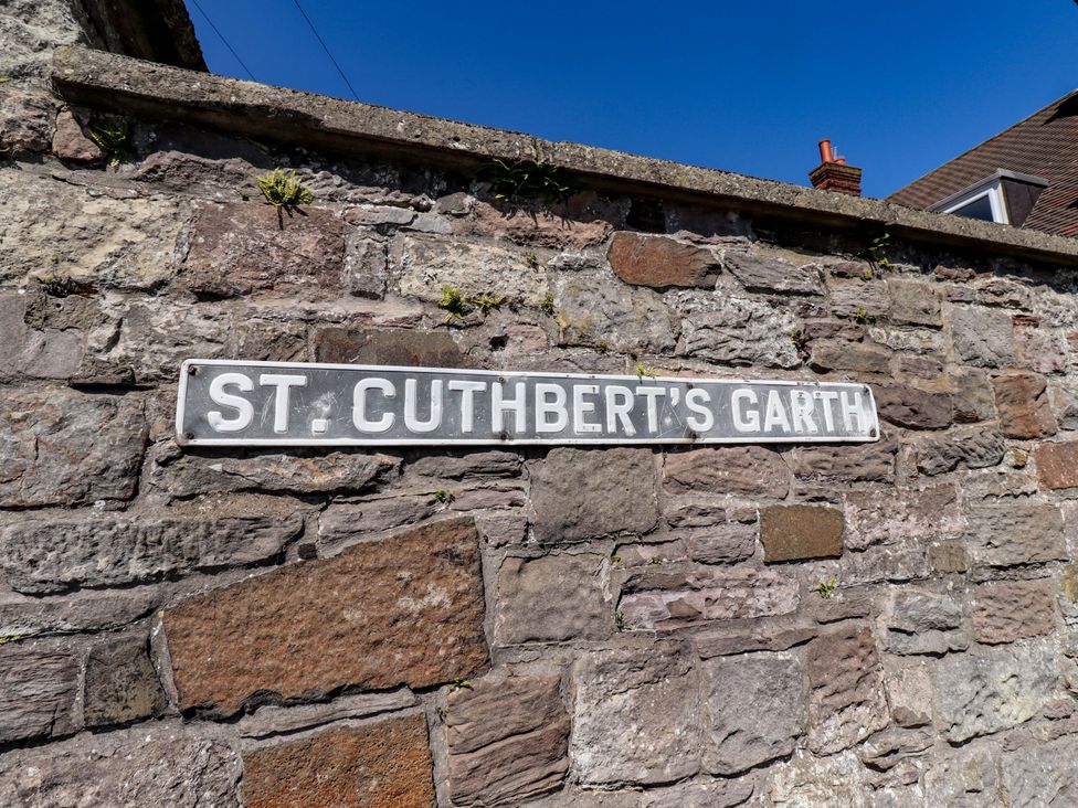 A street sign labeled St. Cuthbert's Garth on a stone wall