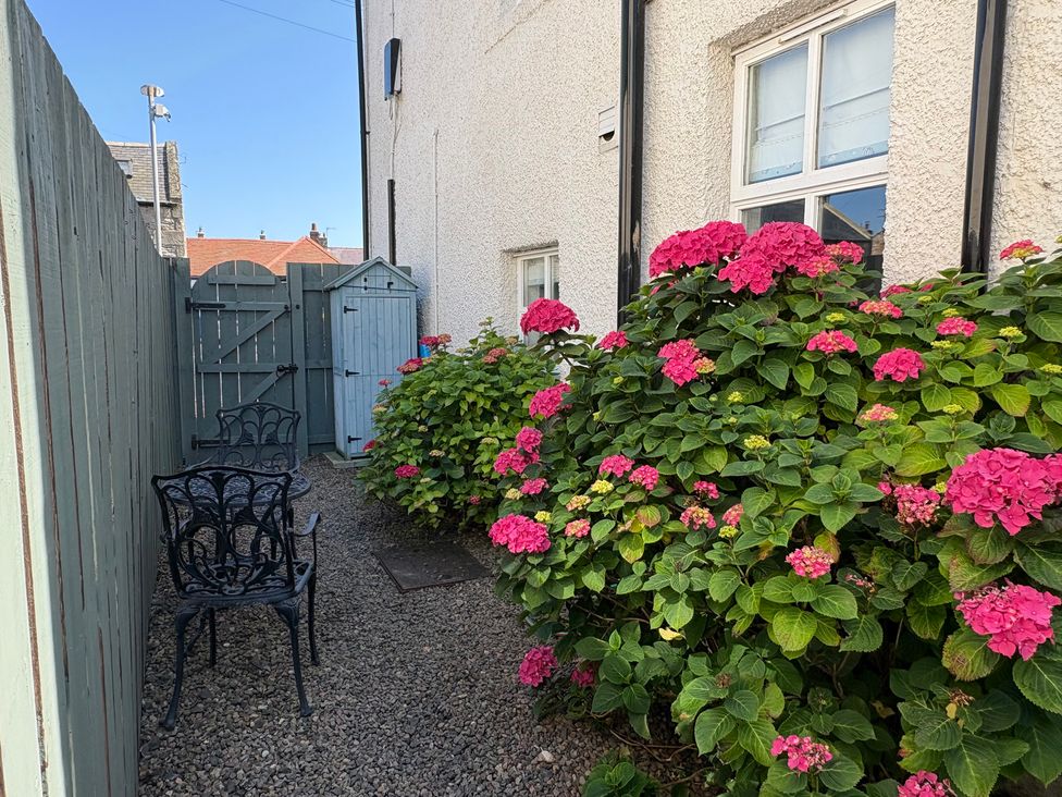 A garden with flowers and seating at Anchor Cottage (Seahouses) in Seahouses