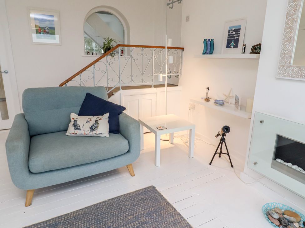 A living room with a chair, table and lamp at Dell Point in Beadnell