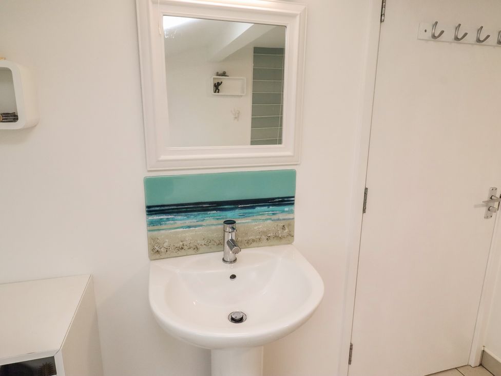 A sink with a mirror and splashback in the bathroom at Dell Point Beadnell