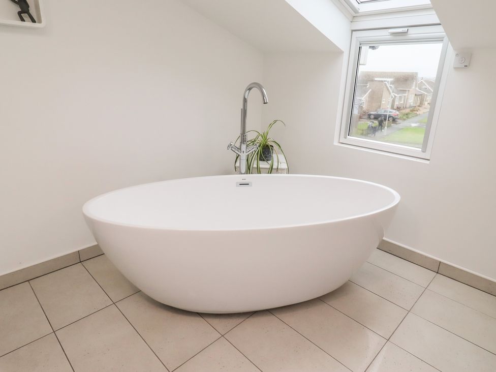 A bathroom with a bathtub and window at Dell Point Beadnell
