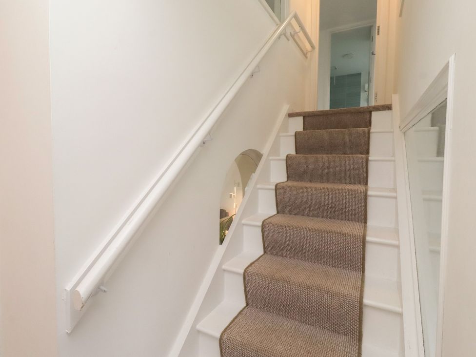 A staircase with carpet and handrail at Dell Point in Beadnell