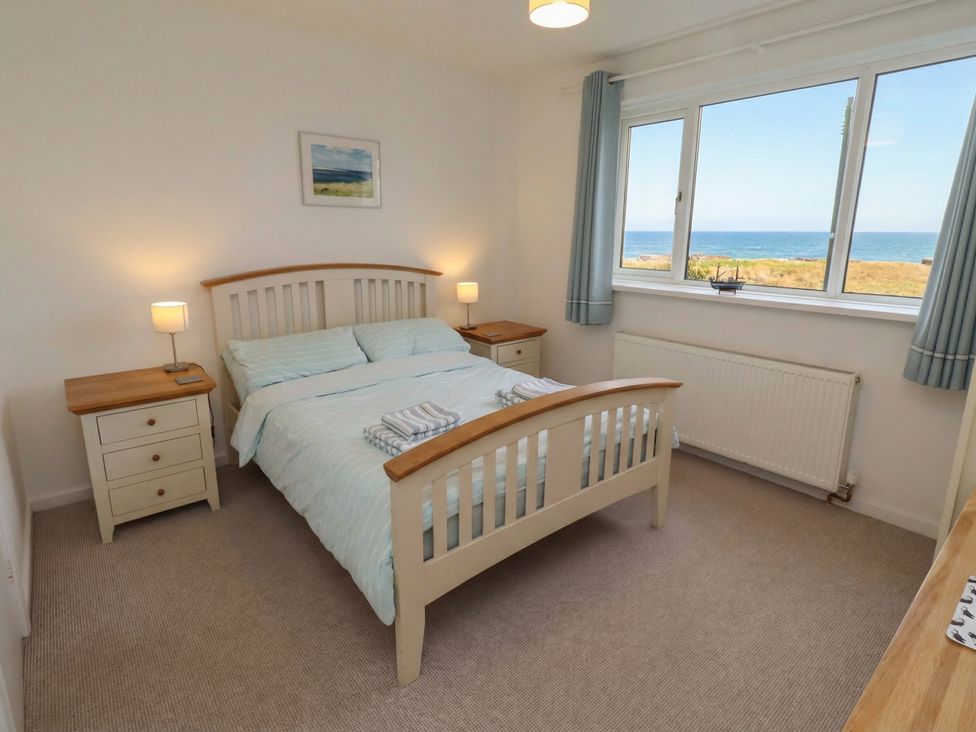 A bedroom with a bed and side tables at Dell Point in Beadnell