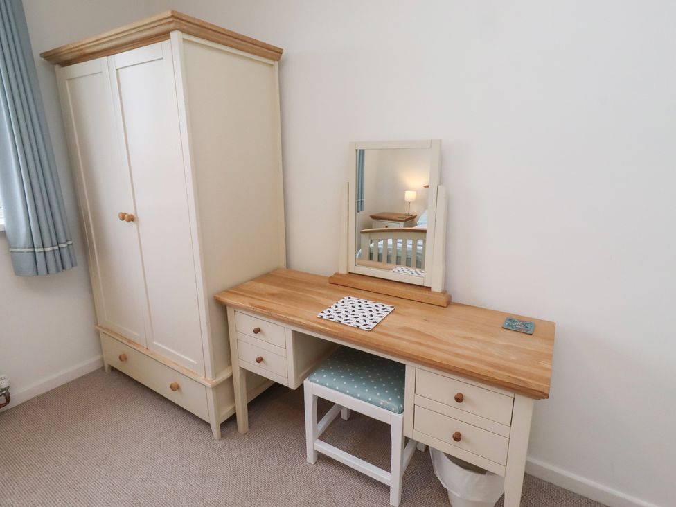 A bedroom with a wardrobe and desk with a mirror at Dell Point in Beadnell