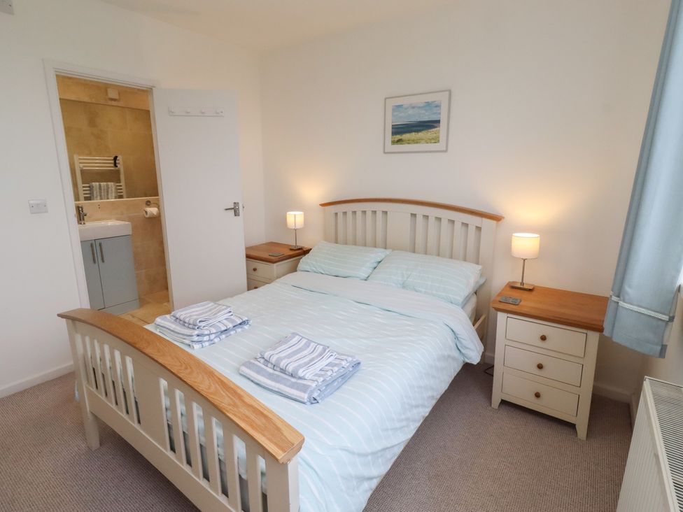 A bedroom with a bed and attached bathroom at Dell Point in Beadnell