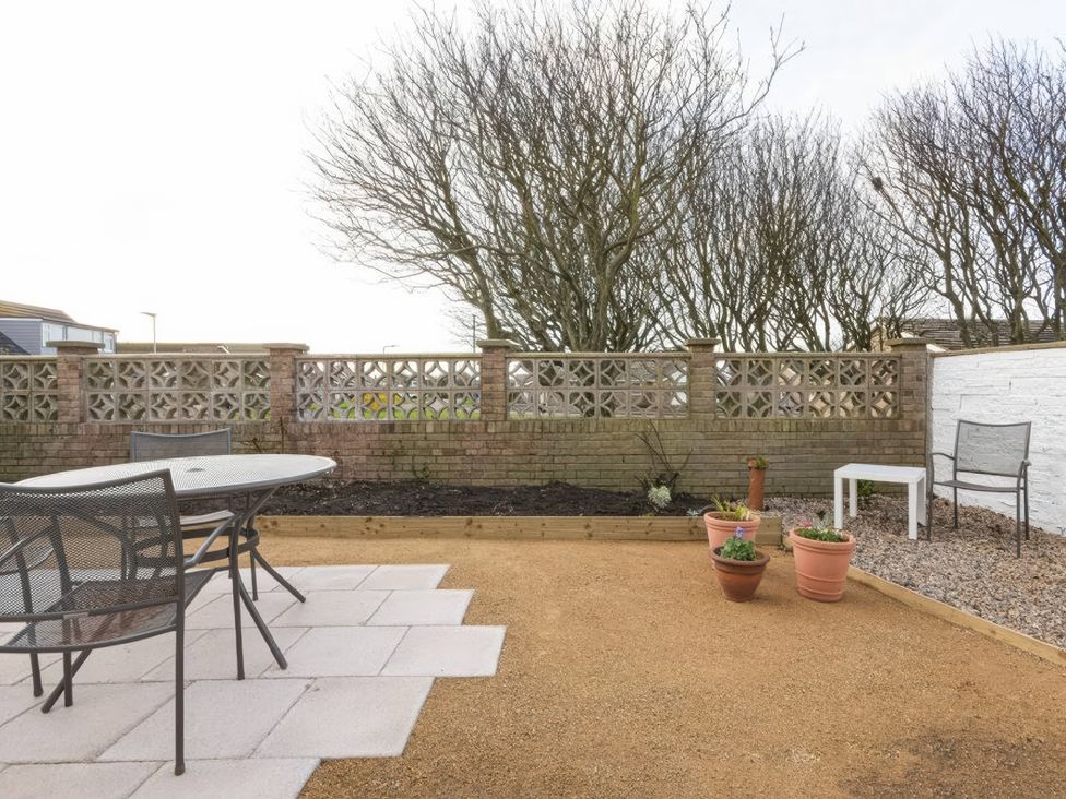 A garden with a table and chairs at Dell Point Beadnell