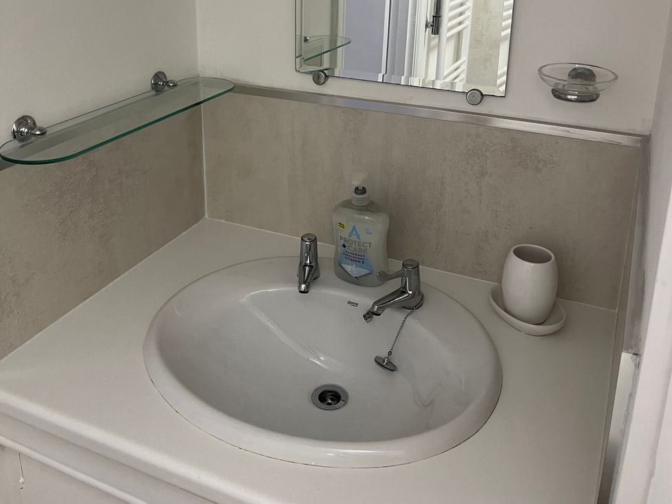 A bathroom sink with mirror and soap dispenser at Old Bakery No2 in Seahouses