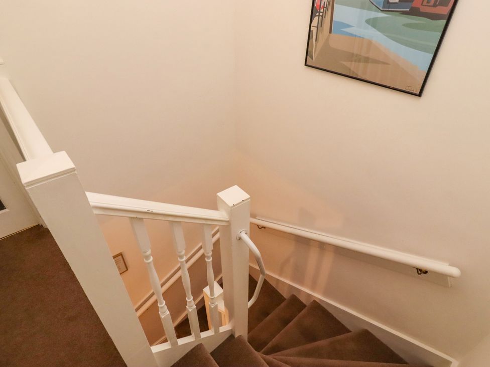 A staircase with handrail and artwork at Old Bakery No2 Seahouses