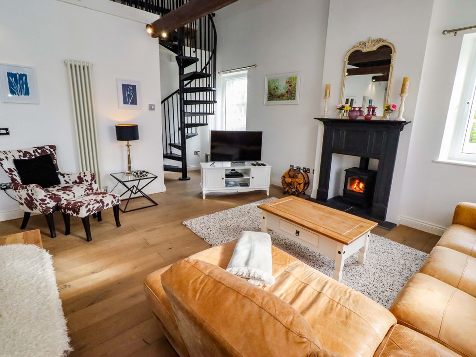 A living room with a sofa, armchair, and television at Treetops, Alnwick