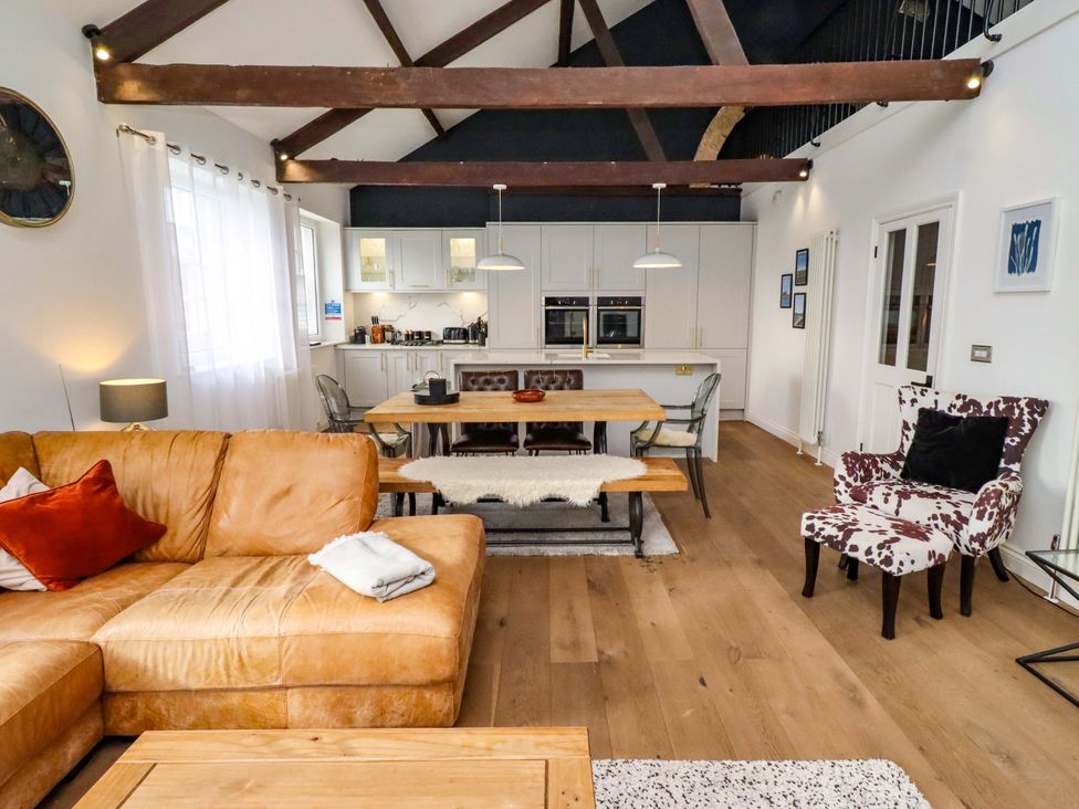 A living room with a sofa, dining area and kitchen at Treetops, Alnwick