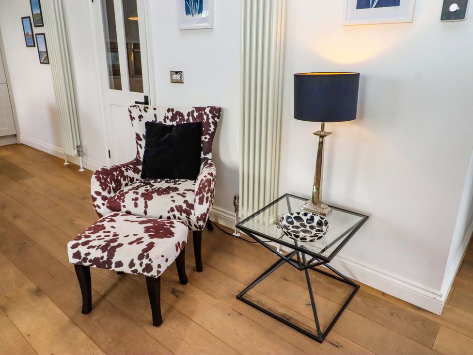 A living room with a chair and side table at Treetops, Alnwick