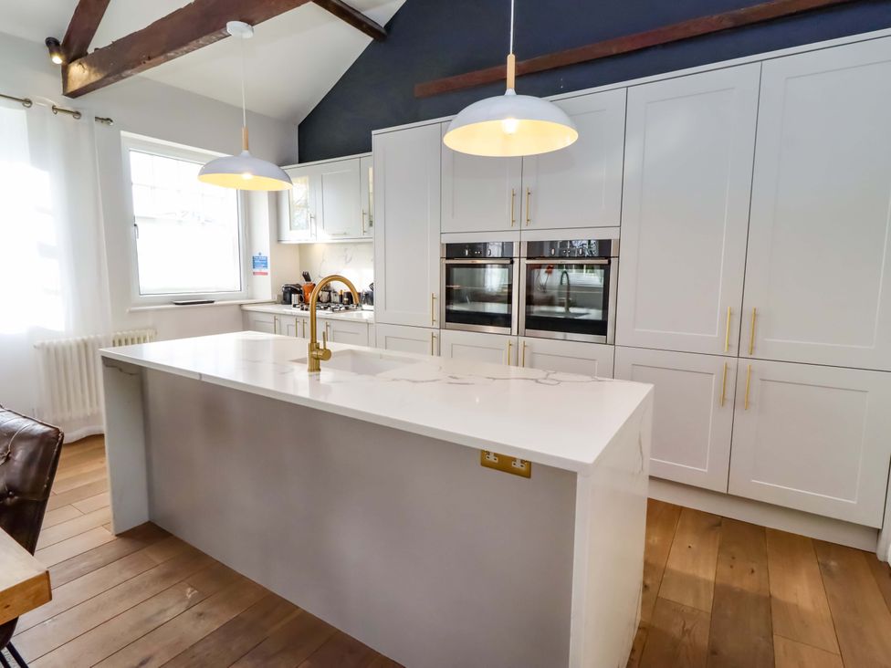 A kitchen with a large island and wall ovens at Treetops, Alnwick