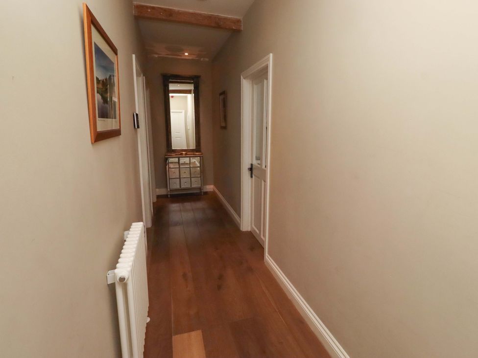 A hallway with a mirror and doors at Treetops, Alnwick
