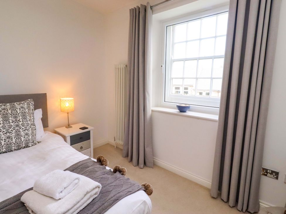 A bedroom with a bed and a lamp at Treetops, Alnwick