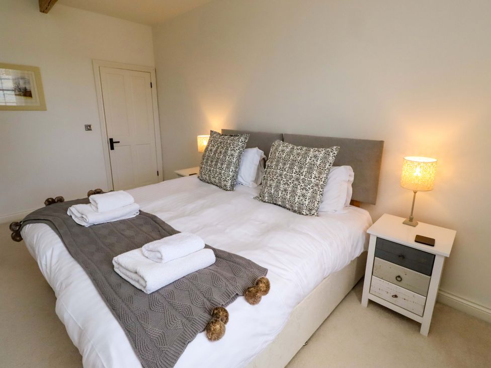 A bedroom with twin beds and bedside table at Treetops, Alnwick