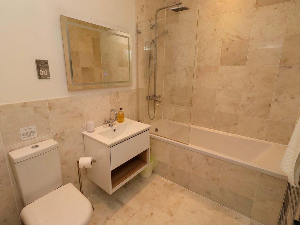 A bathroom with a sink, toilet, bathtub, shower, and mirror at Treetops, Alnwick