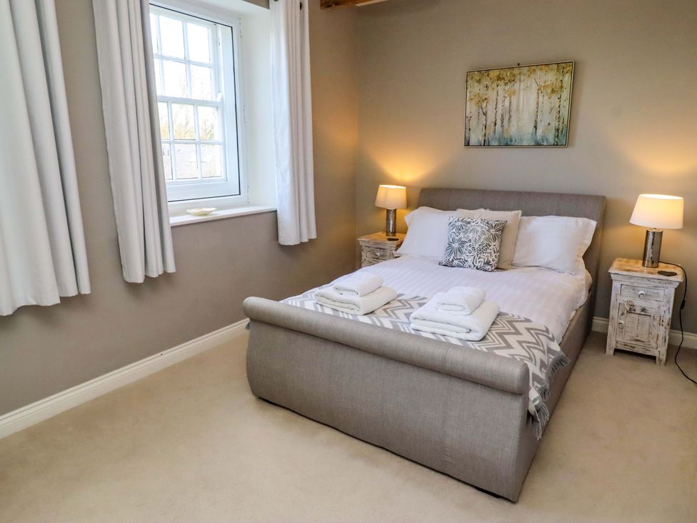 A bedroom with a bed and side tables at Treetops, Alnwick