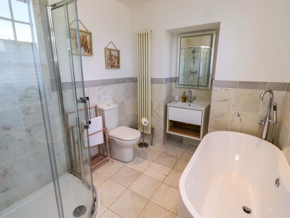 A bathroom with a shower, bathtub, toilet and sink at Treetops, Alnwick
