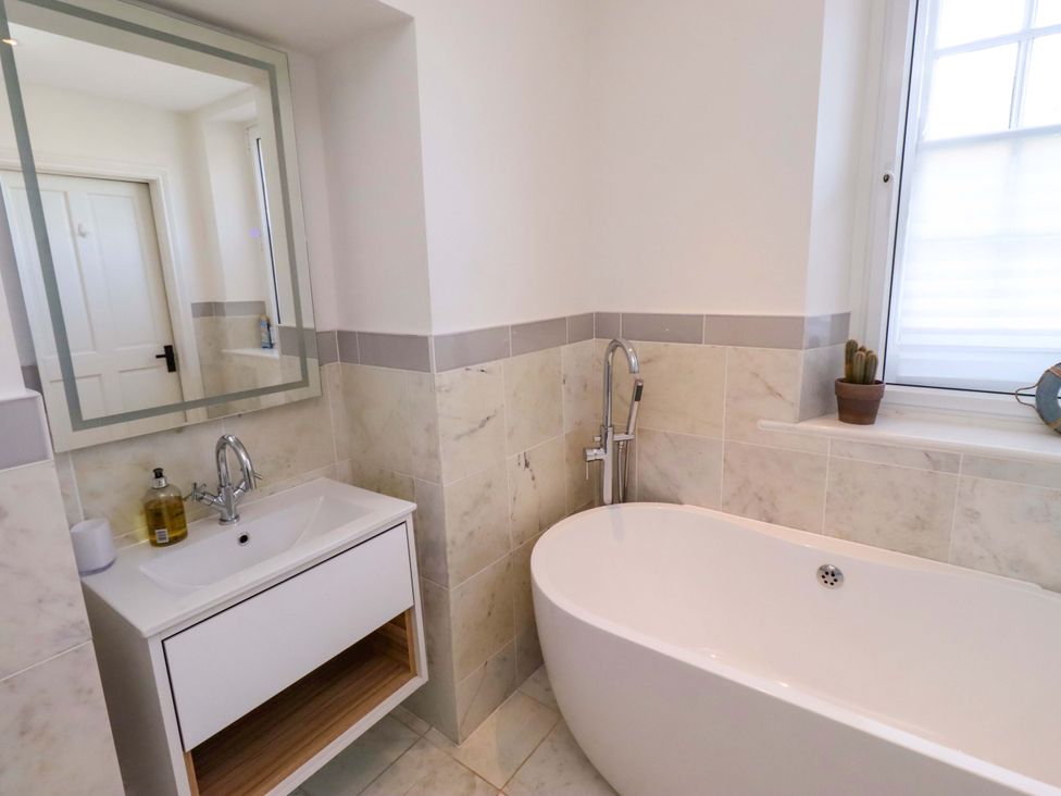 A bathroom with a bathtub and vanity sink at Treetops, Alnwick