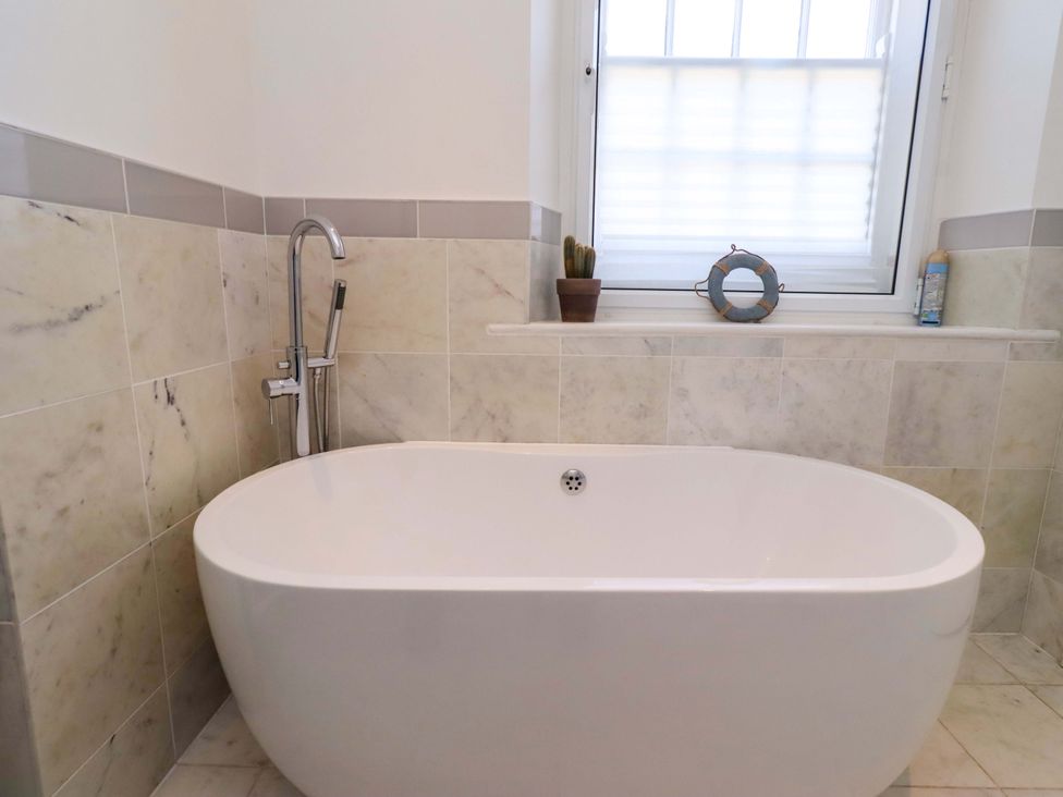 A bathroom with a bathtub and window at Treetops, Alnwick