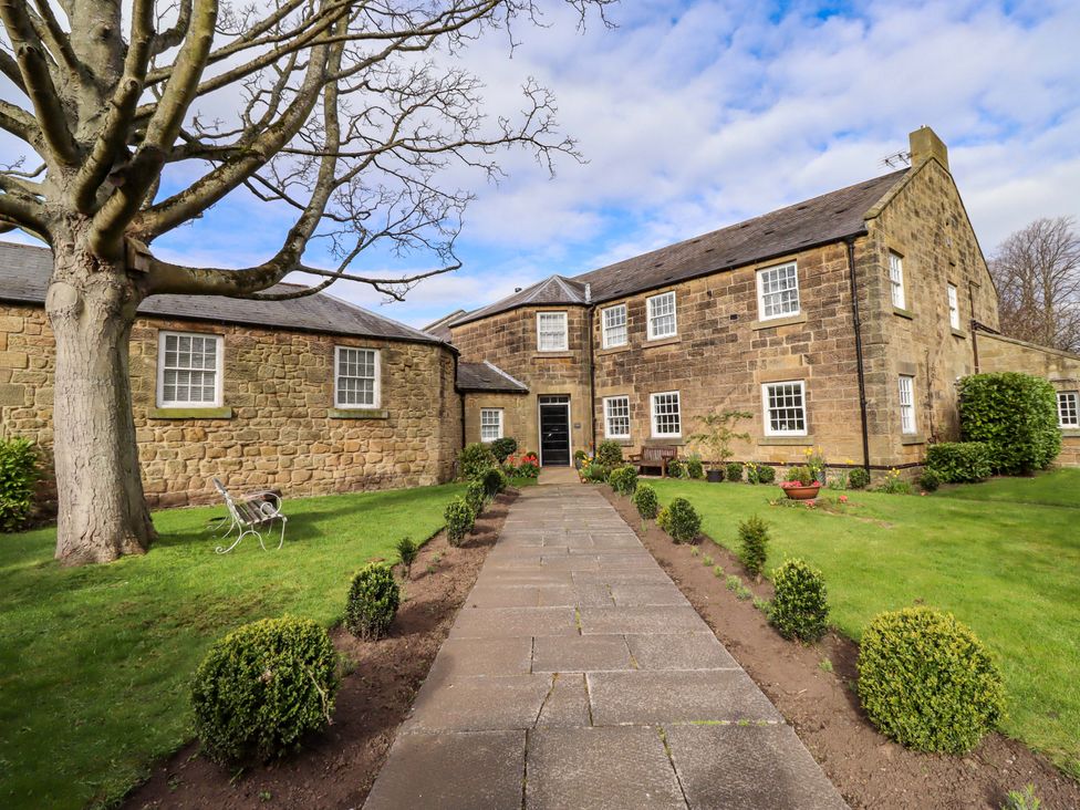 An outdoor view of a building with a path and landscaping at Treetops, Alnwick