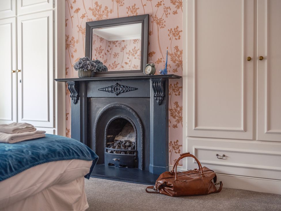 A bedroom with a fireplace and mirror at Westhill House Warkworth