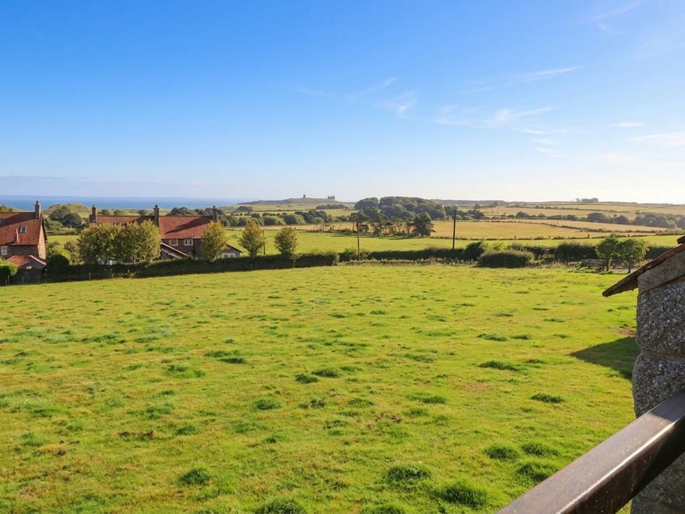 A view of houses and greenery with the ocean in the background at Links View in Embleton