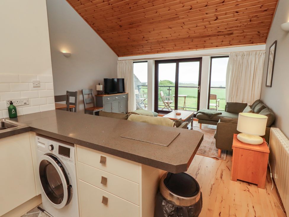 A living room with a kitchen area and seating at Links View in Embleton