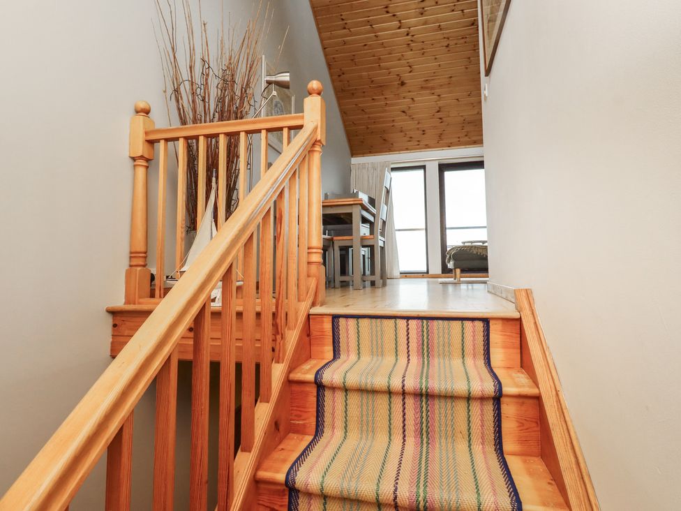 A staircase with a wooden railing and a view of a dining area at Links View in Embleton