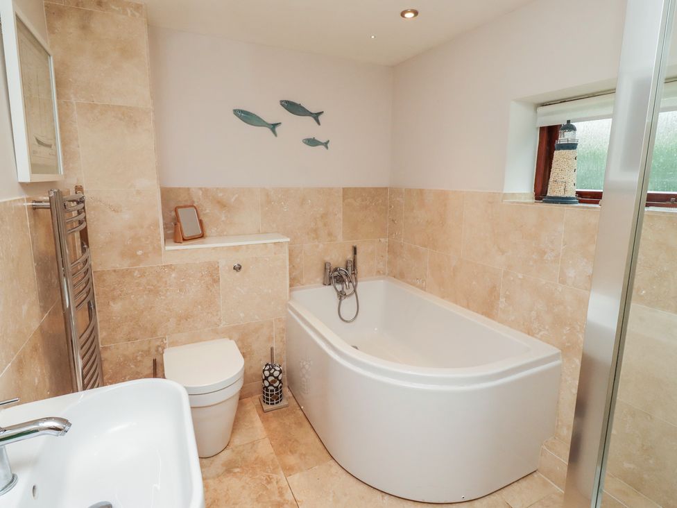 A bathroom with a bathtub, toilet, and sink at Links View in Embleton