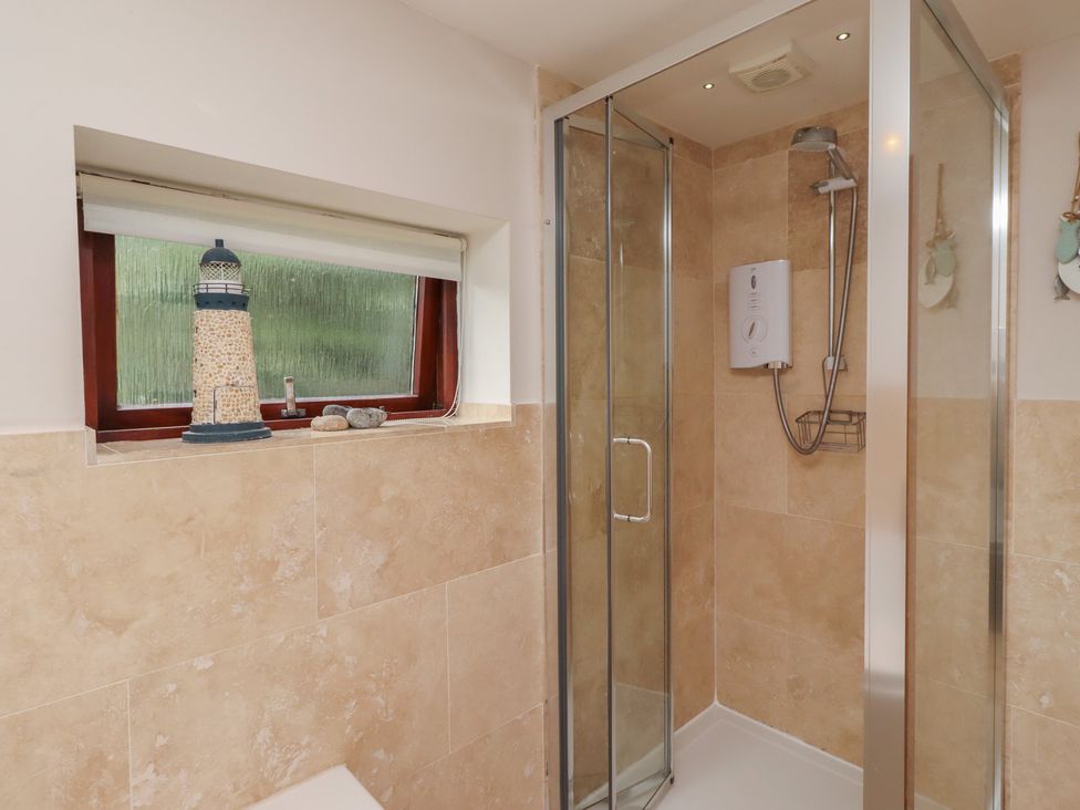 A bathroom with a shower and lighthouse decor at Links View in Embleton