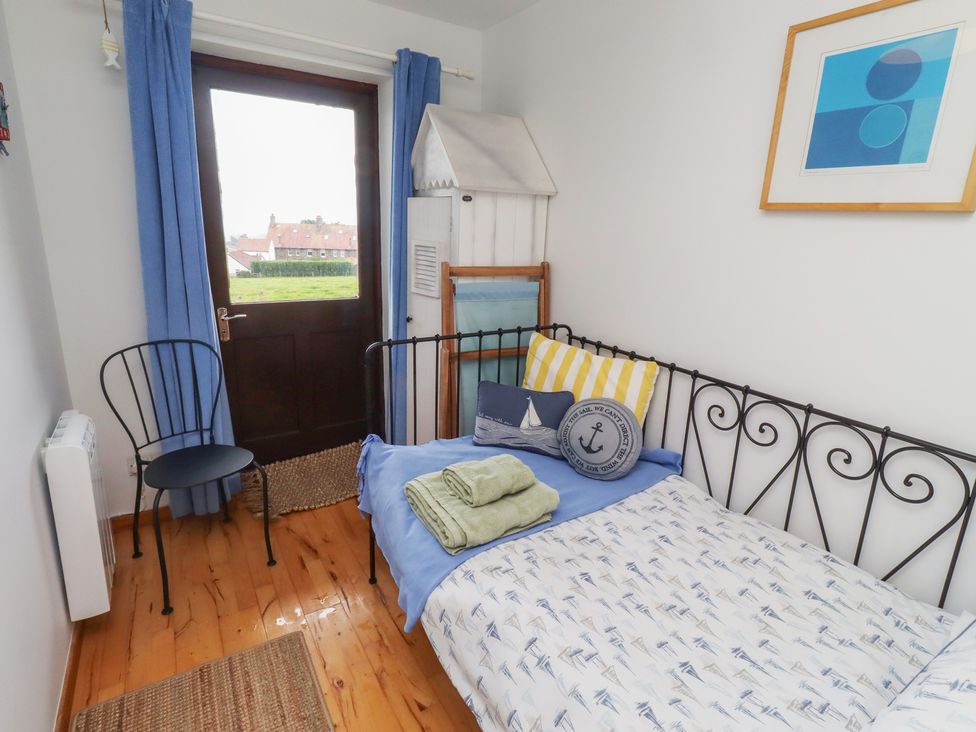 A bedroom with a bed and chair at Links View in Embleton