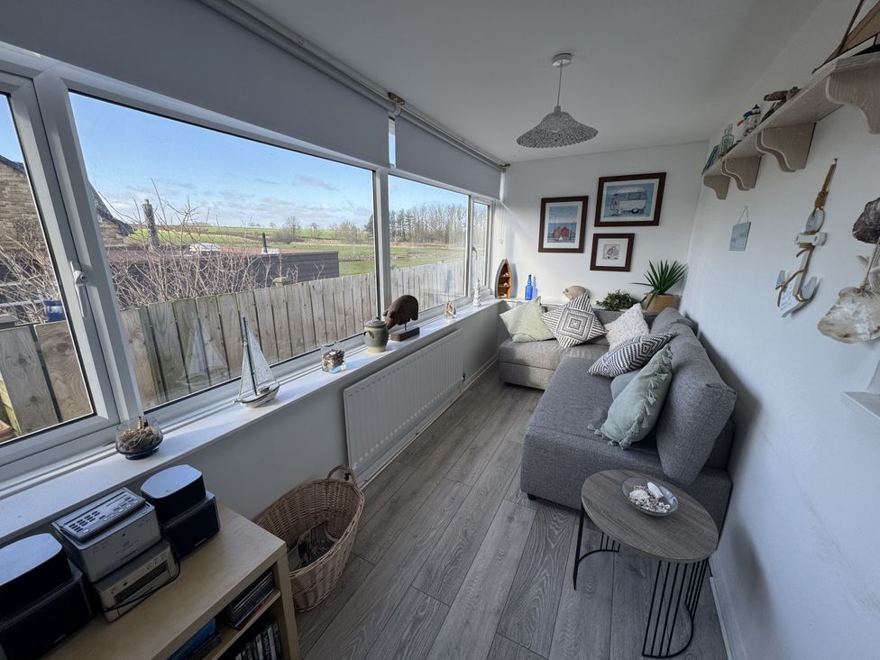 A snug with a sofa and window at Sea Croft in Beadnell