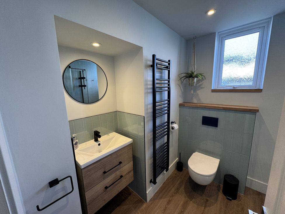 A bathroom with a sink, mirror, and toilet at Sea Croft in Beadnell
