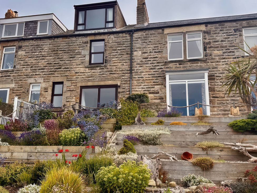 A garden with a stone building and plants at Old Coastguard Cottages in Amble