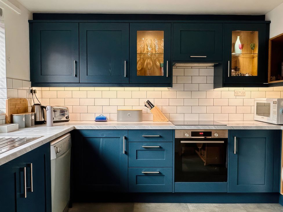 A kitchen with cabinets and appliances at Old Coastguard Cottages Amble