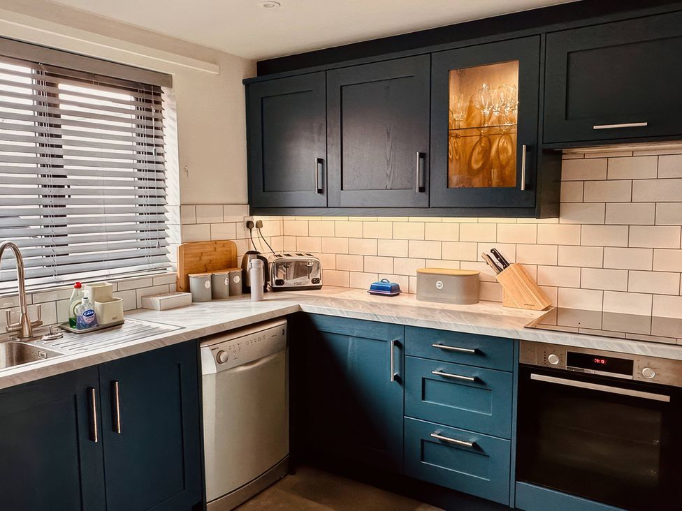 A kitchen with cabinets and appliances at Old Coastguard Cottages Amble