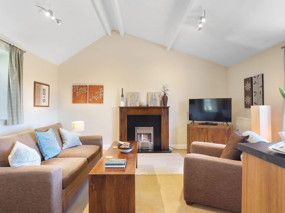 A living room with a sofa, coffee table, and television at Plumtree Cottage in Alnmouth