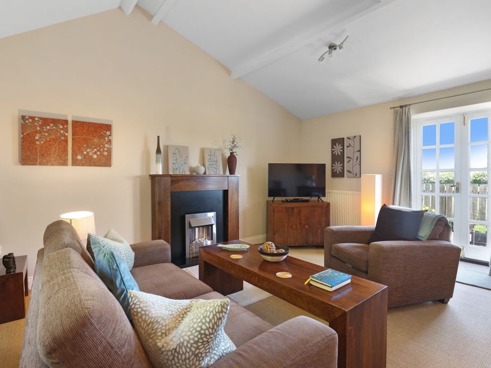 A living room with a sofa and television at Plumtree Cottage in Alnmouth