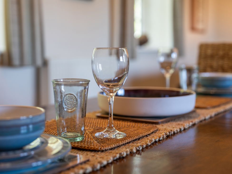 A dining table with glassware and dishware at Plumtree Cottage in Alnmouth